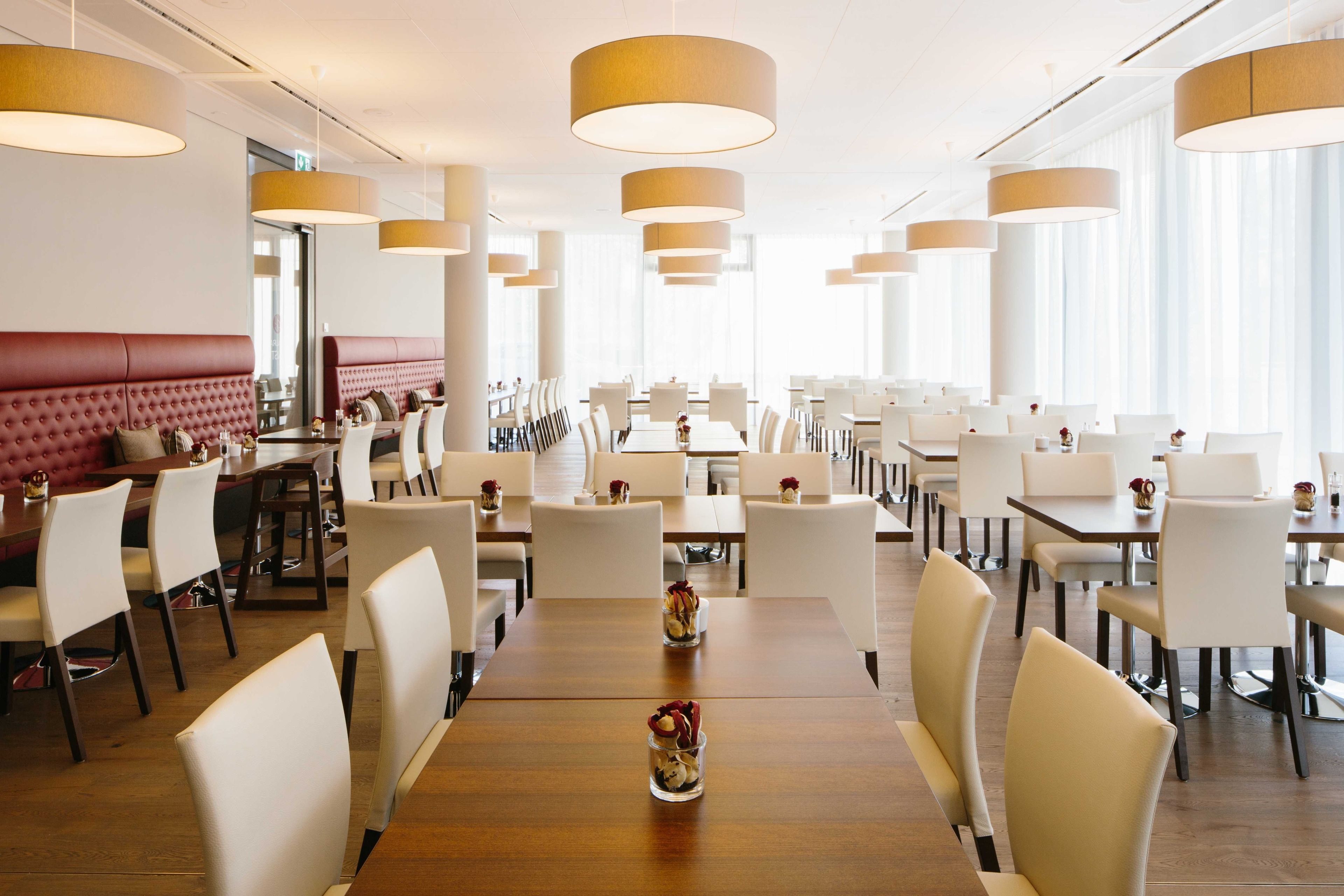 A spacious restaurant with high ceilings, modern pendant lighting, and a mix of booth and table seating.