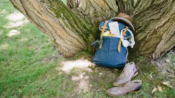 A backpack, a pair of shoes, and a map leaning against a tree.