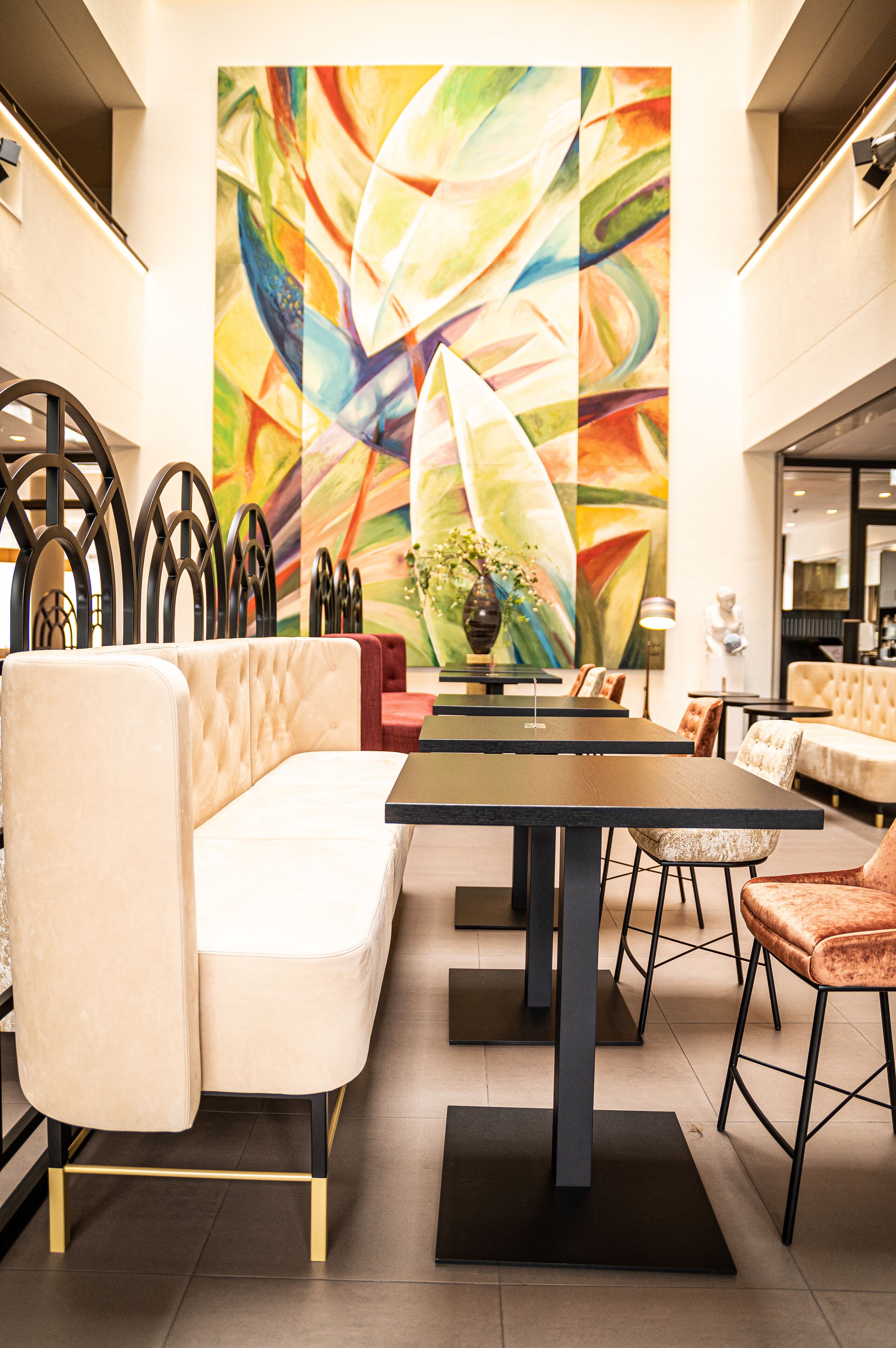 Un interno moderno con zona pranzo, caratterizzato da un grande quadro astratto, un divano e un tavolo con sedie.