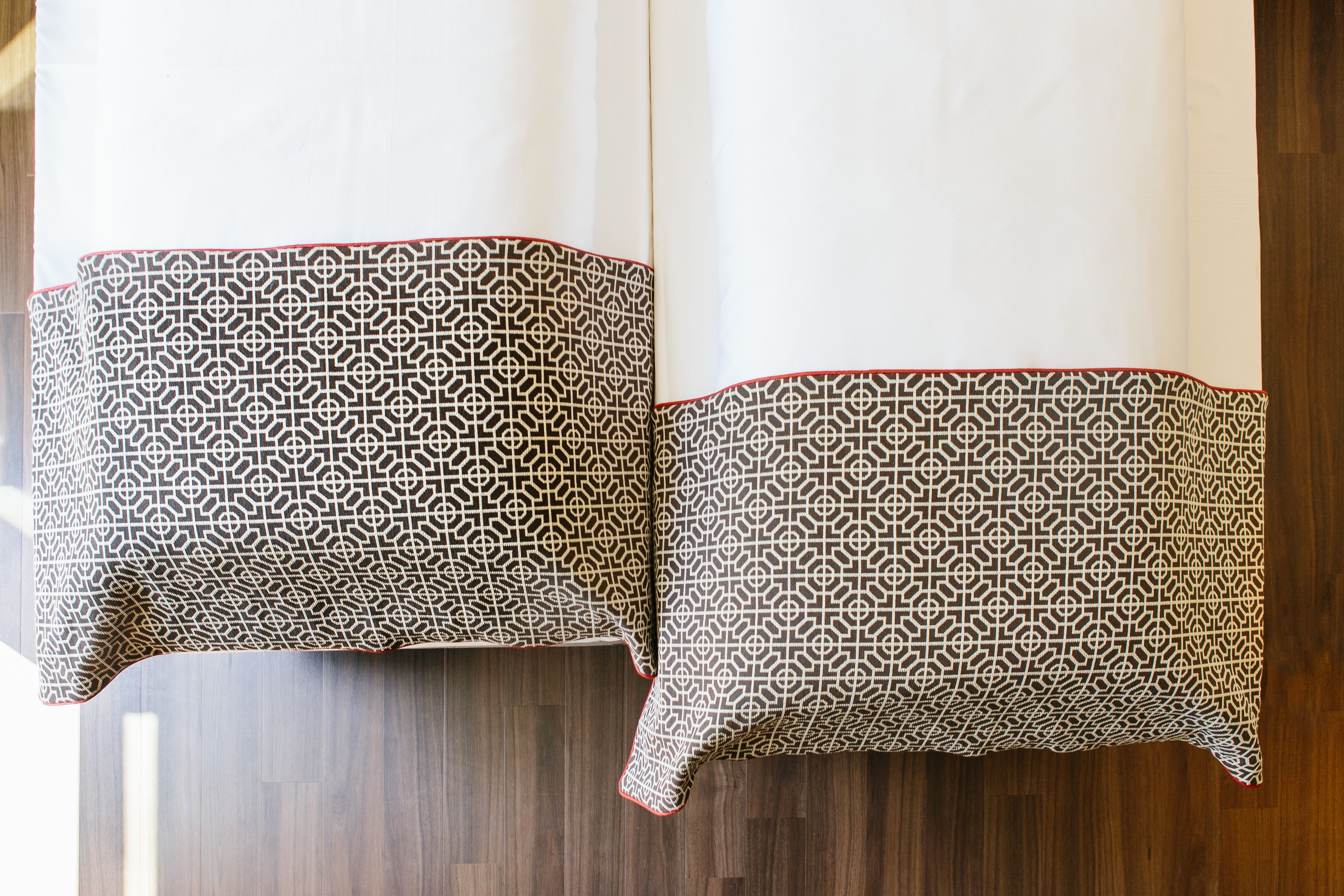 Ein Zimmer mit Holzboden und einem Tisch, der mit zwei gemusterten Tischdecken drapiert ist.