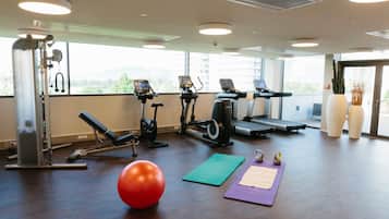 Une salle de sport équipée de matériel d’exercice, avec un ballon rouge et un tapis vert.