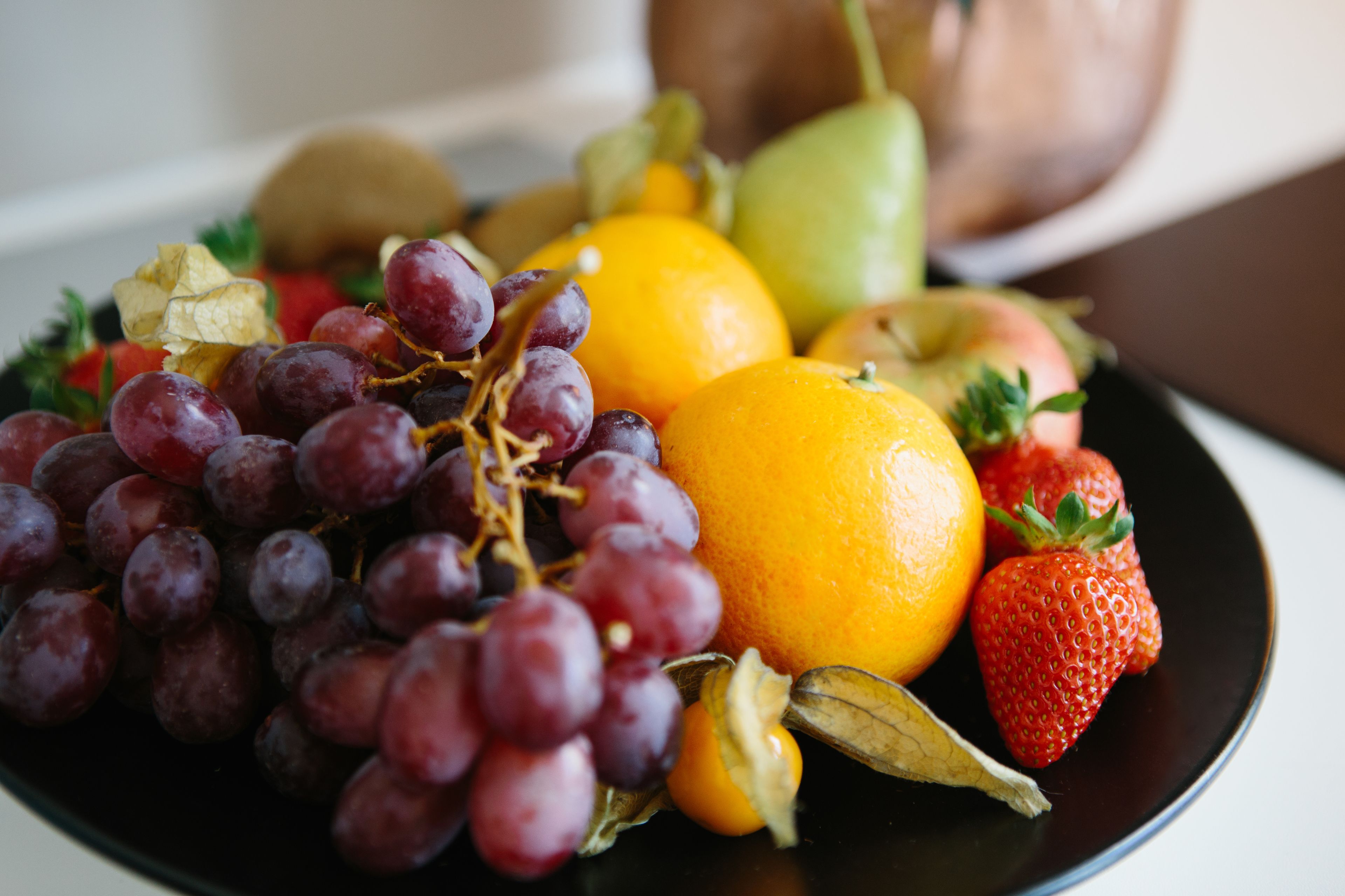 A plate of assorted fruits including grapes, oranges, strawberries, and a kiwi.