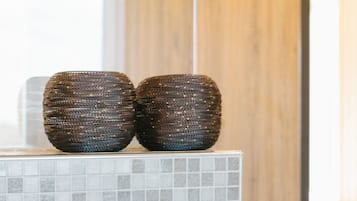 A bathroom with a tiled wall, two woven baskets on a counter, and a wooden panel in the background.