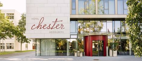 A modern hotel building with a prominent sign reading "HOTEL chester HEIDELBERG".