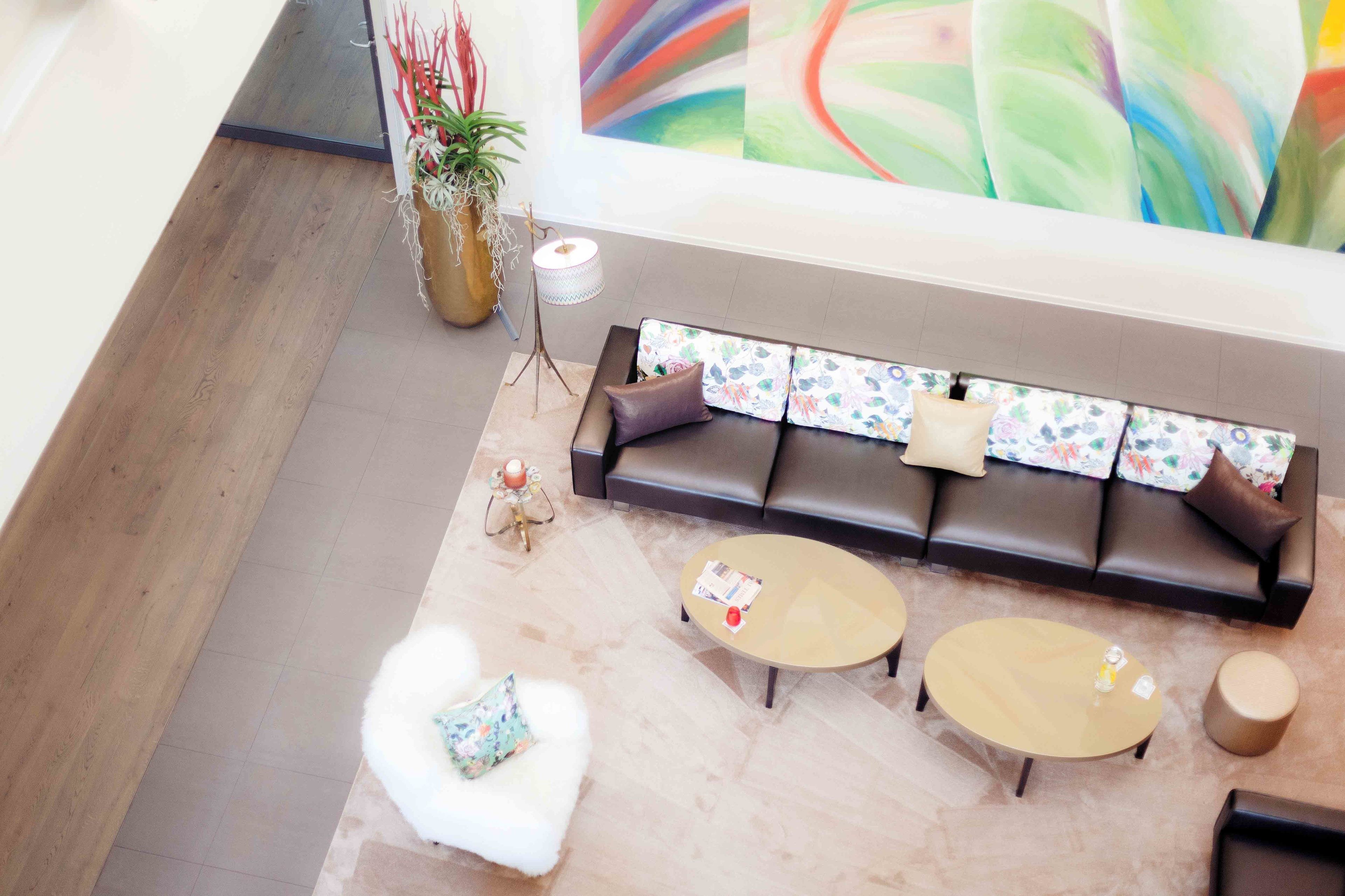 Una sala de estar moderna con un sofá, dos mesas redondas de centro y un sillón blanco y mullido.
