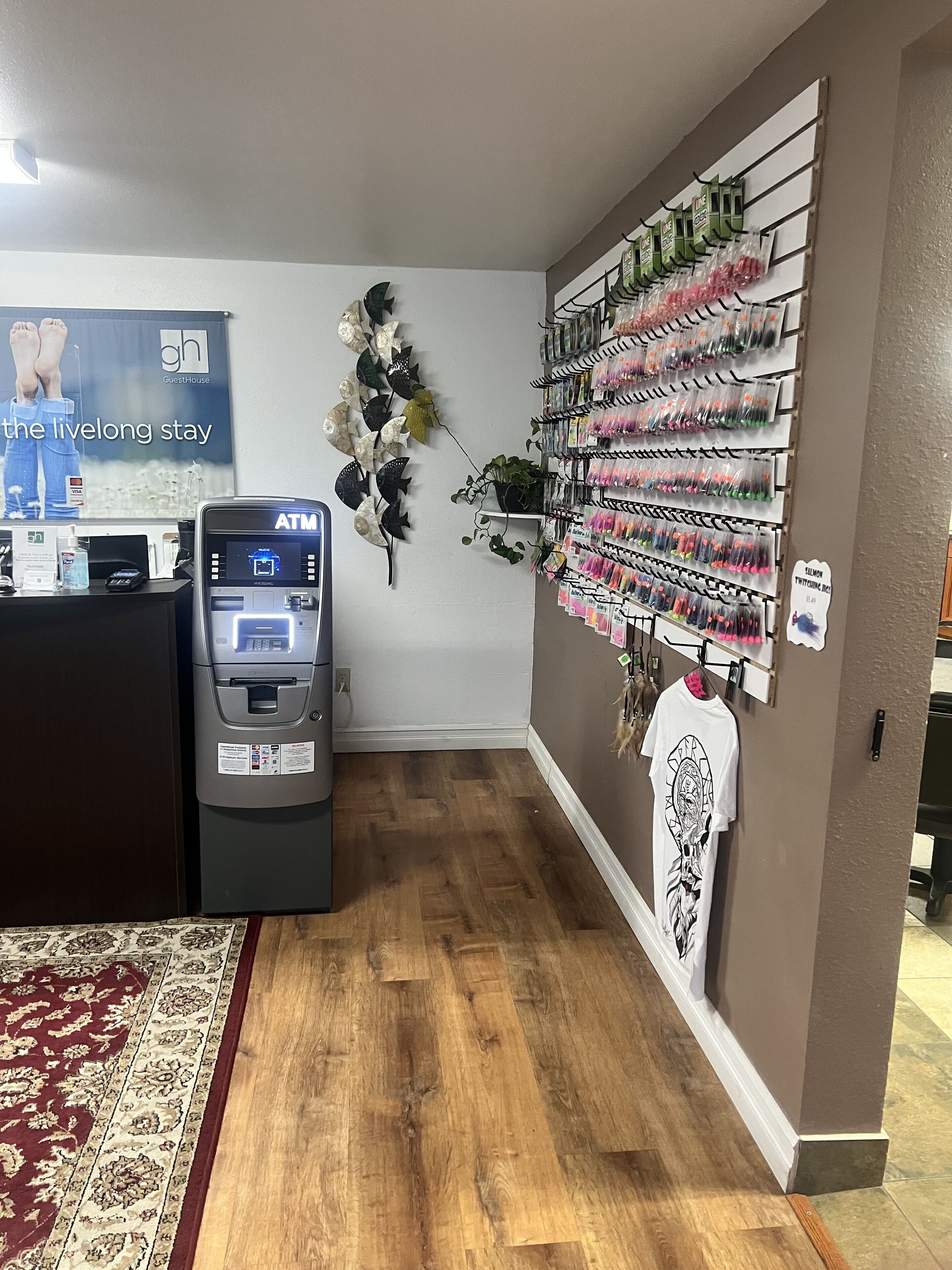 A hotel lobby with a reception desk, ATM, decorative wall art, and a wall display of toiletries.