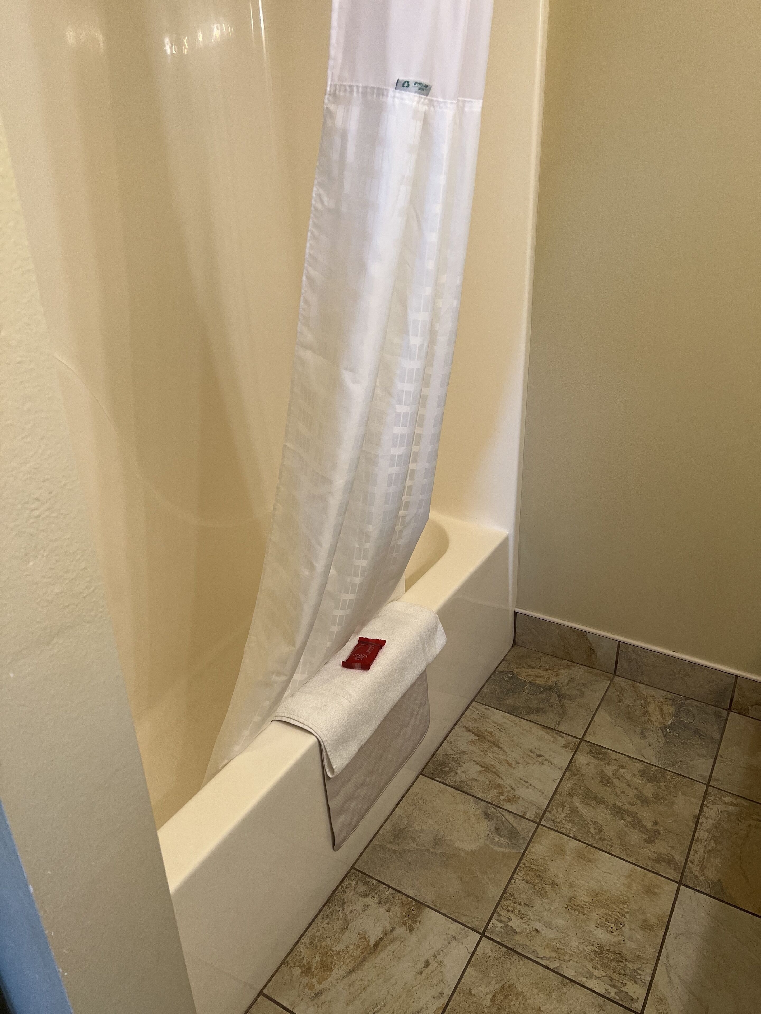 A bathroom with a bathtub, a shower curtain, and tiled flooring.