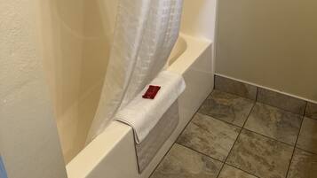A bathroom with a bathtub, a shower curtain, and tiled flooring.