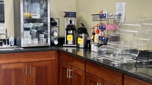 A kitchenette with a coffee machine, a milk frother, and a refrigerator.