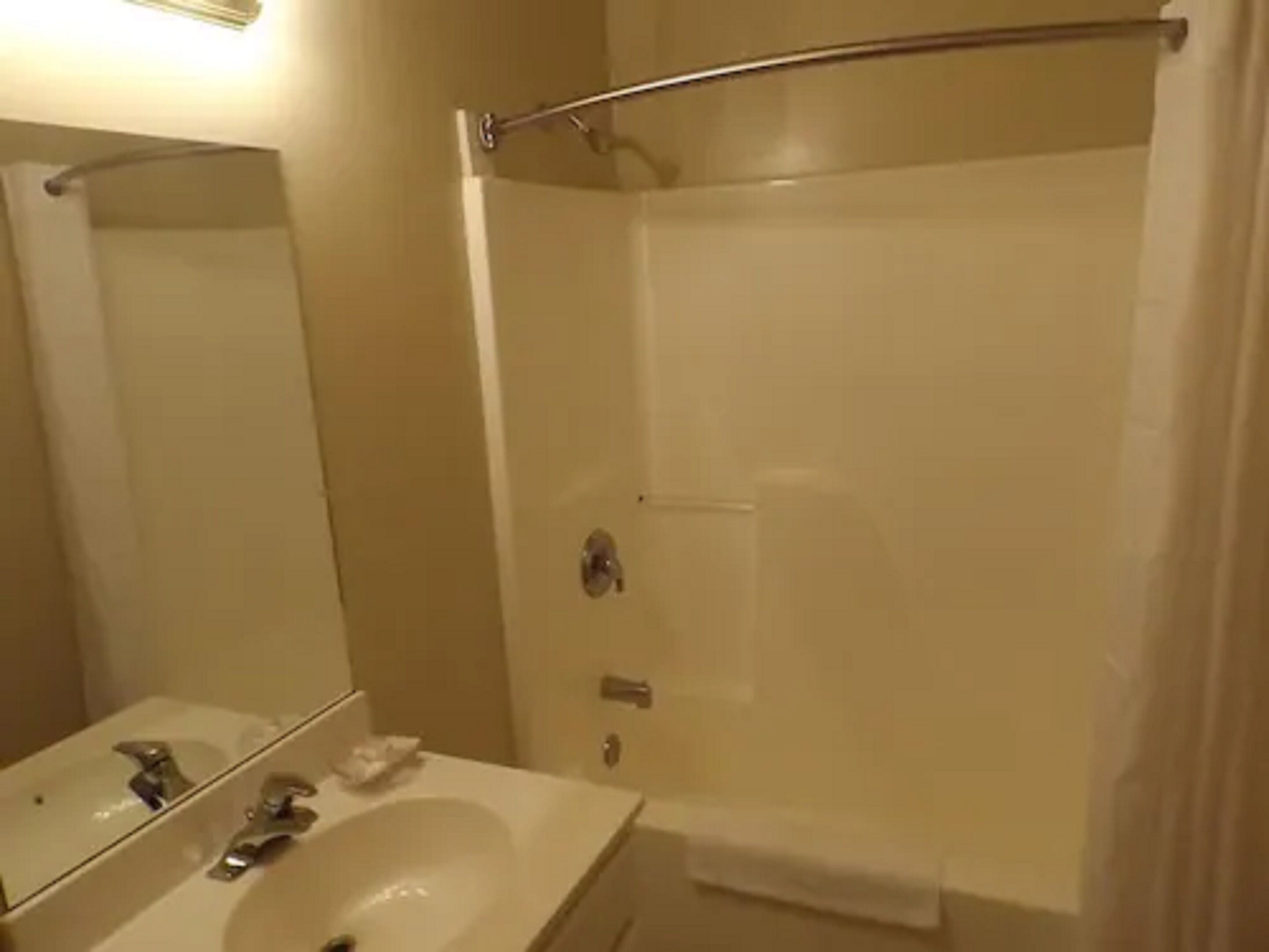A bathroom with a sink, mirror, and shower.