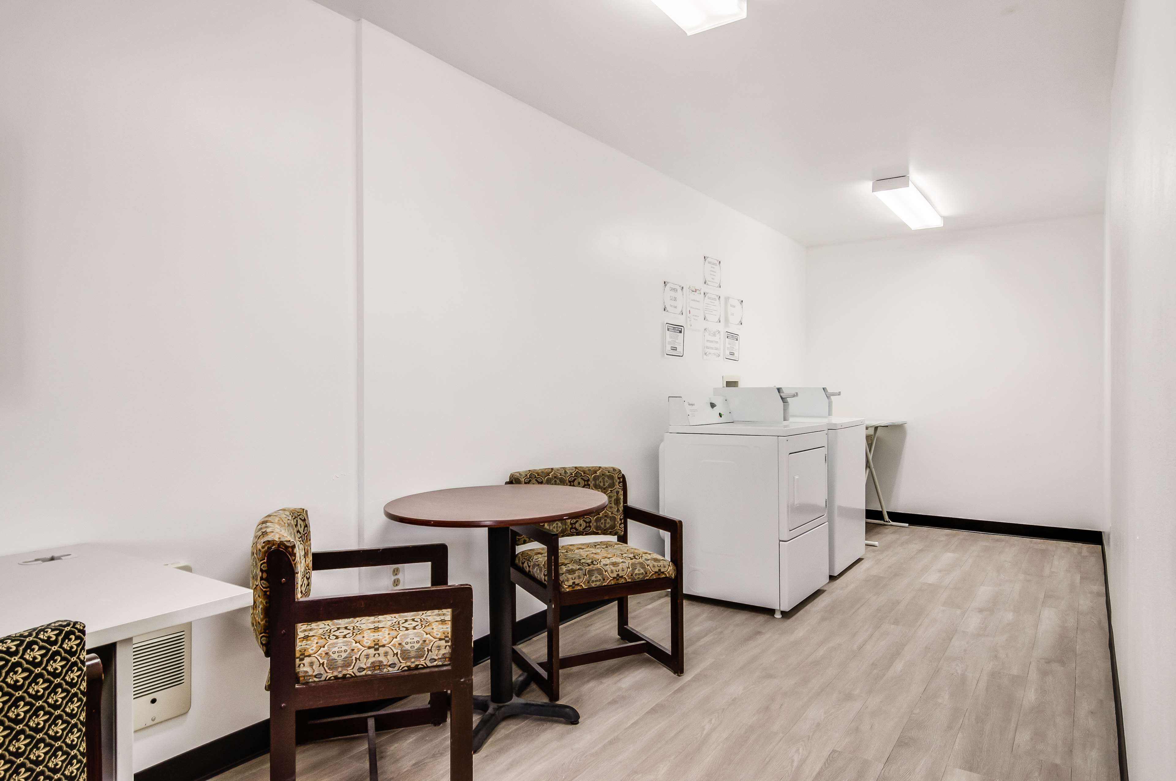 Une petite pièce moderne avec une table ronde et deux chaises à motifs, un meuble blanc et un luminaire au plafond.
