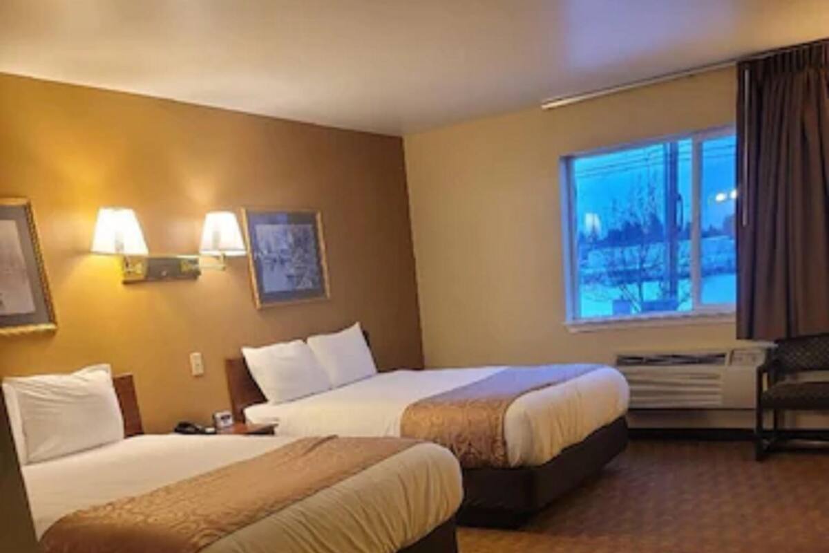 A hotel room with two beds, a window with a view, and a desk with a chair.