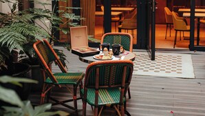 An outdoor seating area with wicker chairs and a table, surrounded by potted plants. - Hôtel Eiffel Blomet (Paris)