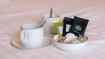 Een keurig opgemaakt ontbijt op een bed, bestaande uit een witte mok, een kom cornflakes en twee theezakjes op een witte tafelkleed.