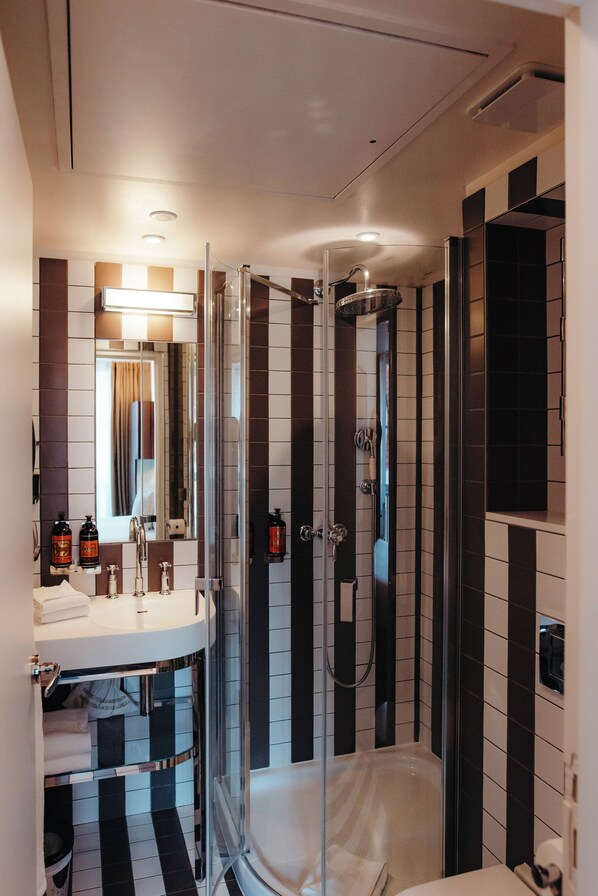 Une salle de bain moderne avec une douche à l’italienne en verre, un meuble-lavabo avec un miroir et un carrelage noir et blanc.