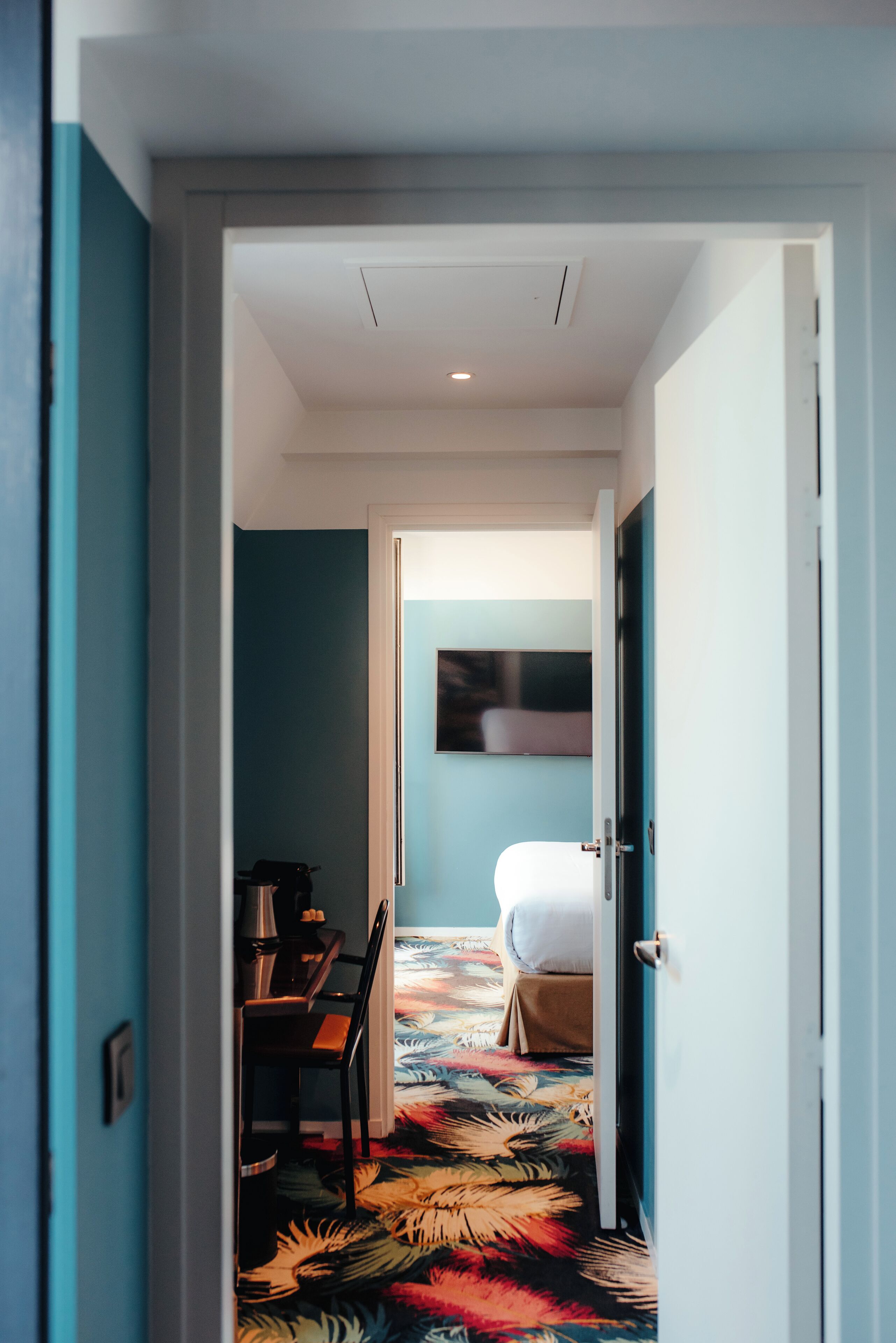 Ein Hotelzimmer mit einem Bett, einem Sessel, einem Tisch und einem farbenfrohen Teppich.