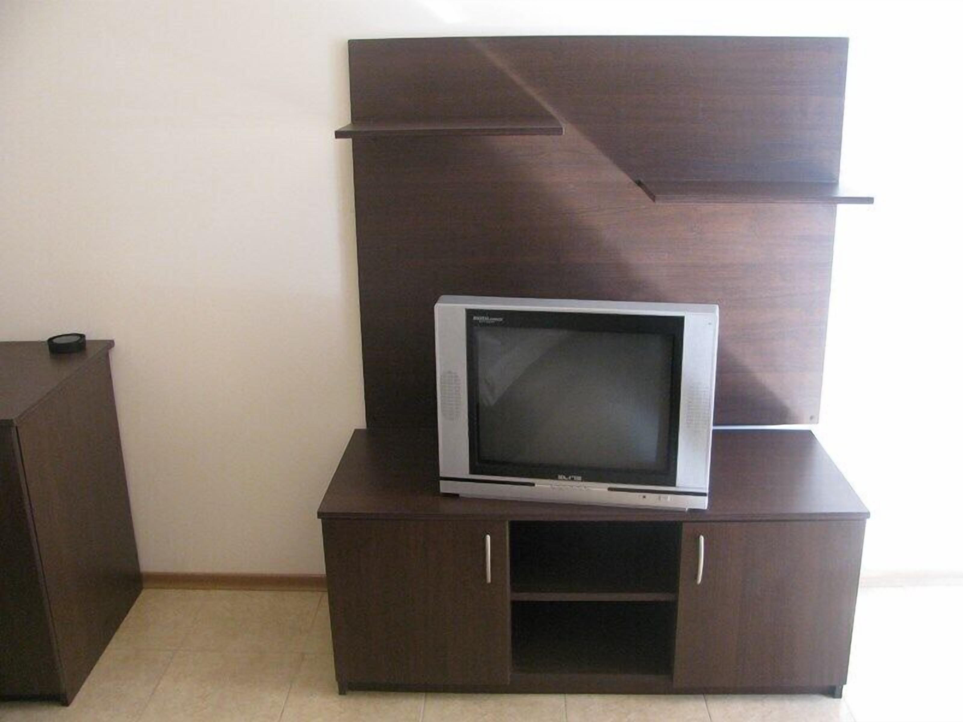 A television on a dark wooden cabinet with a shelf below.