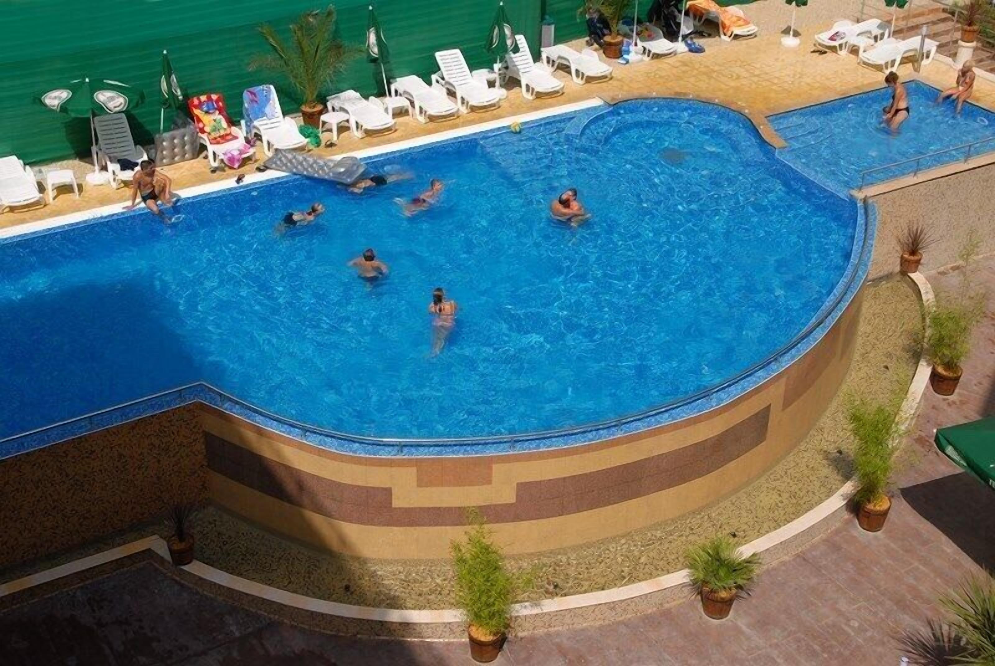 A large, curved swimming pool with multiple people swimming and lounging.