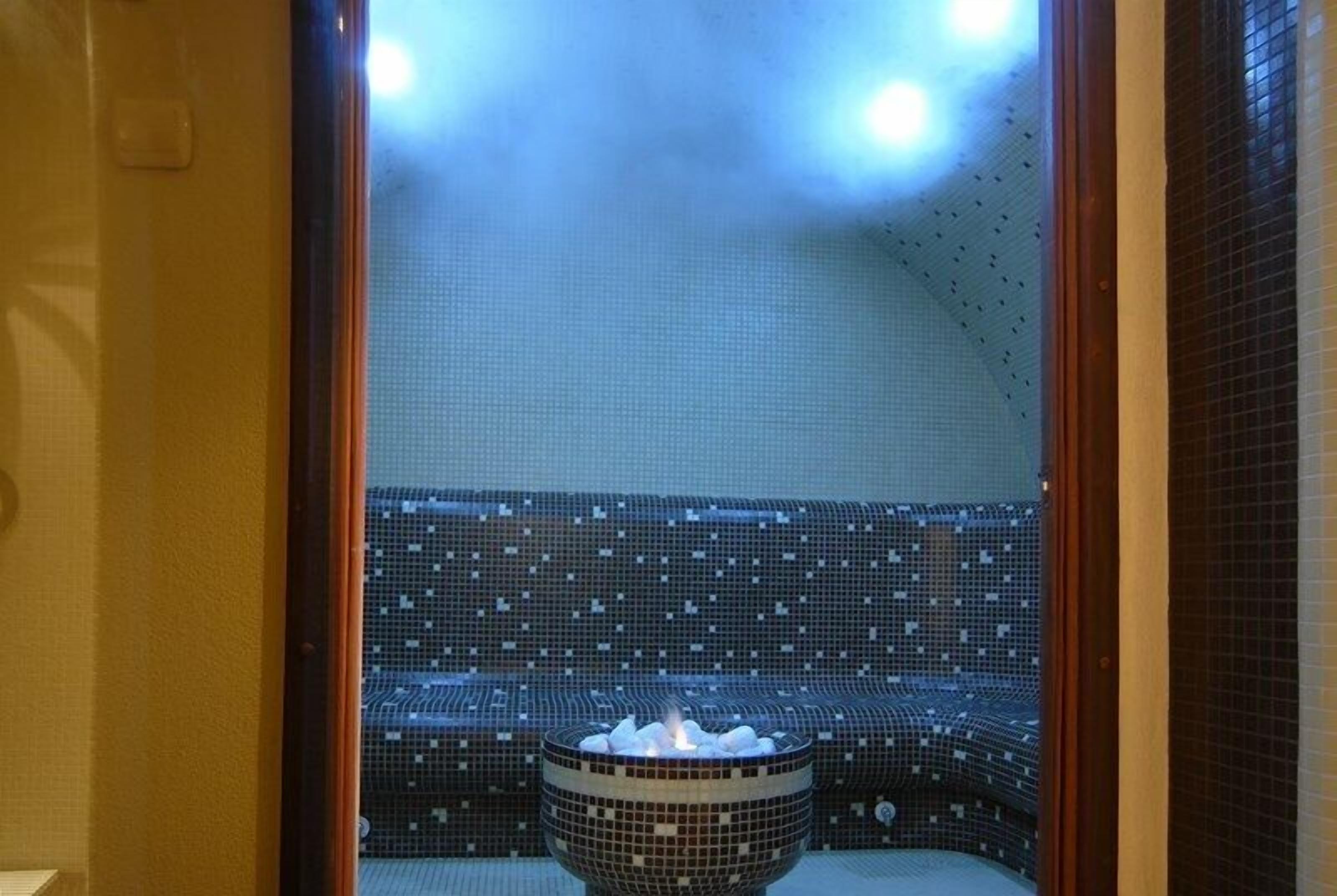 Un sauna avec un mur carrelé et un récipient rempli de pierres chaudes.