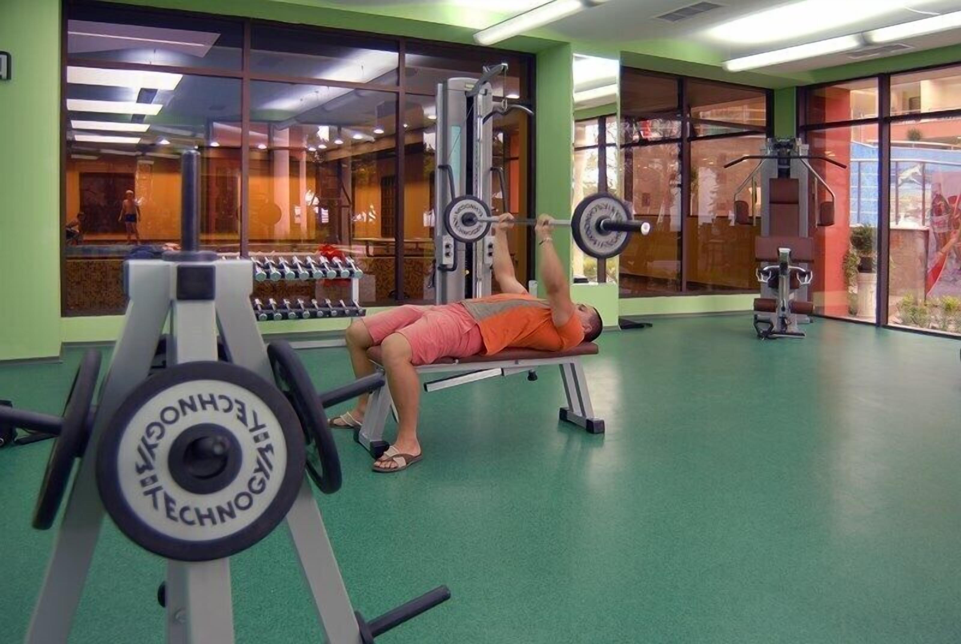 A gym with weightlifting equipment and a person lying on a bench.