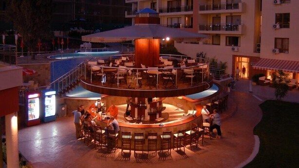 A circular bar area with multiple seating arrangements and a pool in the background. - Hotela Panorama Vigo (Nessebar)
