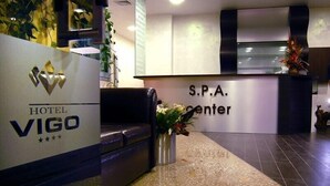 A hotel reception area with a reception desk, a sofa, and a decorative vase with flowers. - Hotela Panorama Vigo (Nessebar)