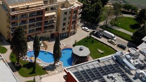 A multi-story hotel with a swimming pool, outdoor seating, and a parking area. - Hotela Panorama Vigo (Nessebar)
