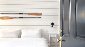 A bedroom with a white bed, a small bedside table, and a black door. - Salt House Inn (Provincetown)