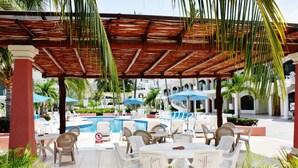 A poolside area with white lounge chairs, a pool, and umbrellas.