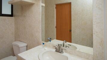 A bathroom with a sink, mirror, toilet, and a shower curtain.