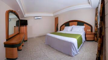 Una habitación de hotel con cama, televisor, escritorio y espejo.