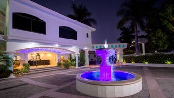 A hotel with a reception area, a fountain, and palm trees.