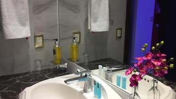 A modern bathroom with a large white sink, marble countertop, and a mirror reflecting the space.