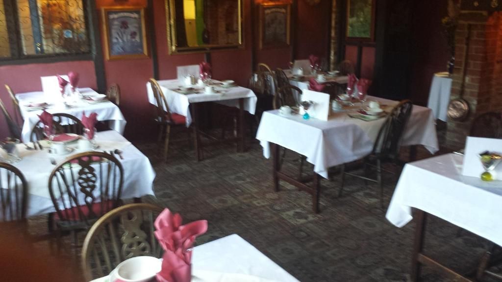 Interior de restaurante con varias mesas dispuestas para comer, sillas y piso con diseño.