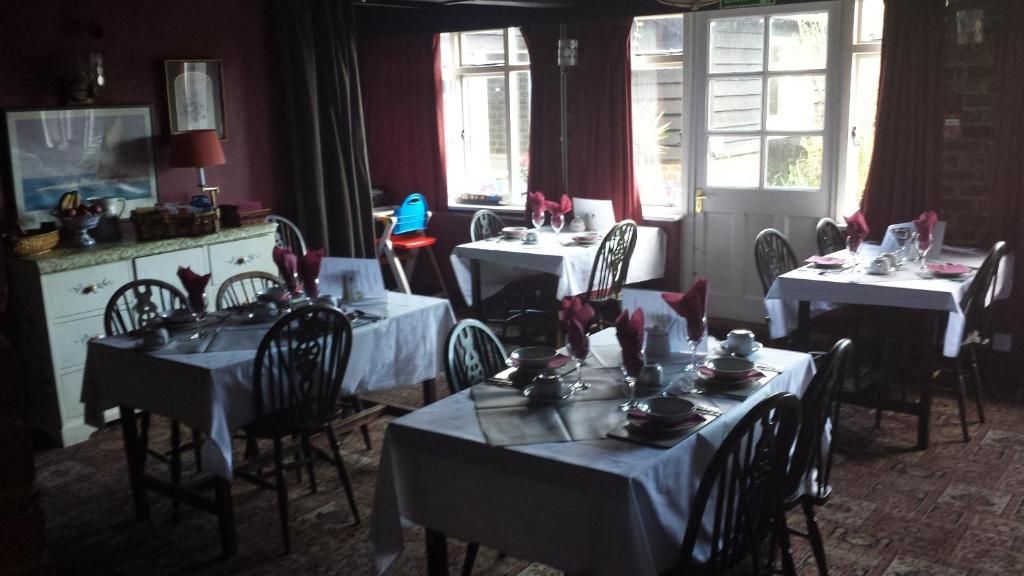 Un espace repas avec plusieurs tables dressées, des chaises et un comptoir où sont exposés des produits.