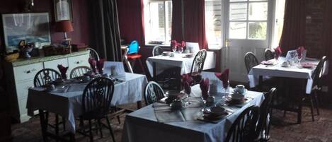 Un espace repas avec plusieurs tables dressées, des chaises et un comptoir où sont exposés des produits.