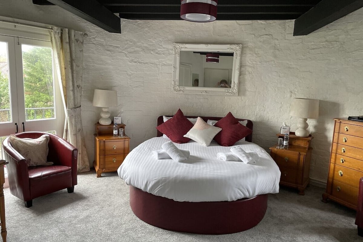 Une chambre à coucher avec un lit rond, une chaise, une commode et une table de chevet.