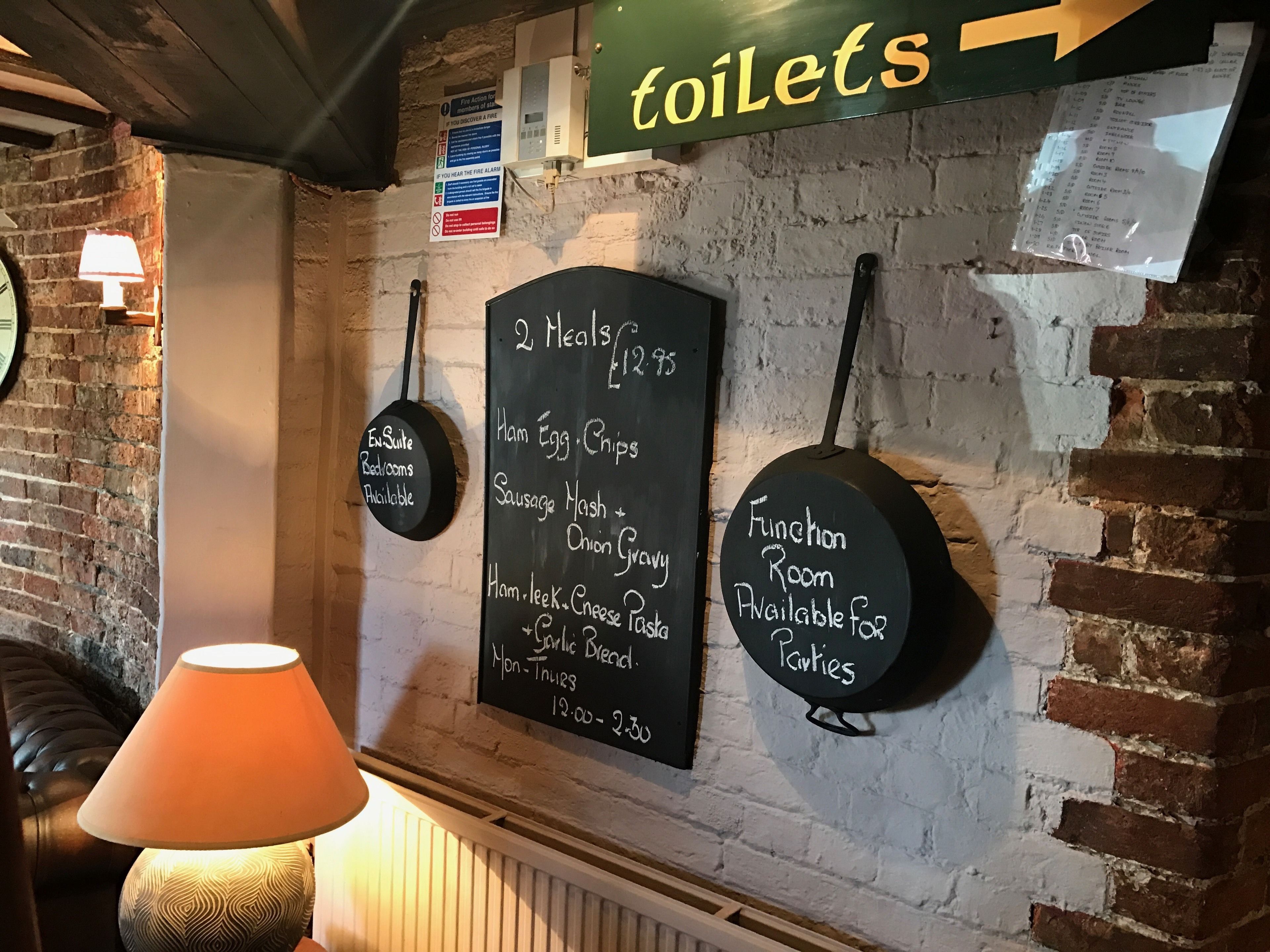 Eine Wand mit Schildern, die eine Toilette, einen Raum für Feiern und eine Speisekarte für Mahlzeiten anzeigen.