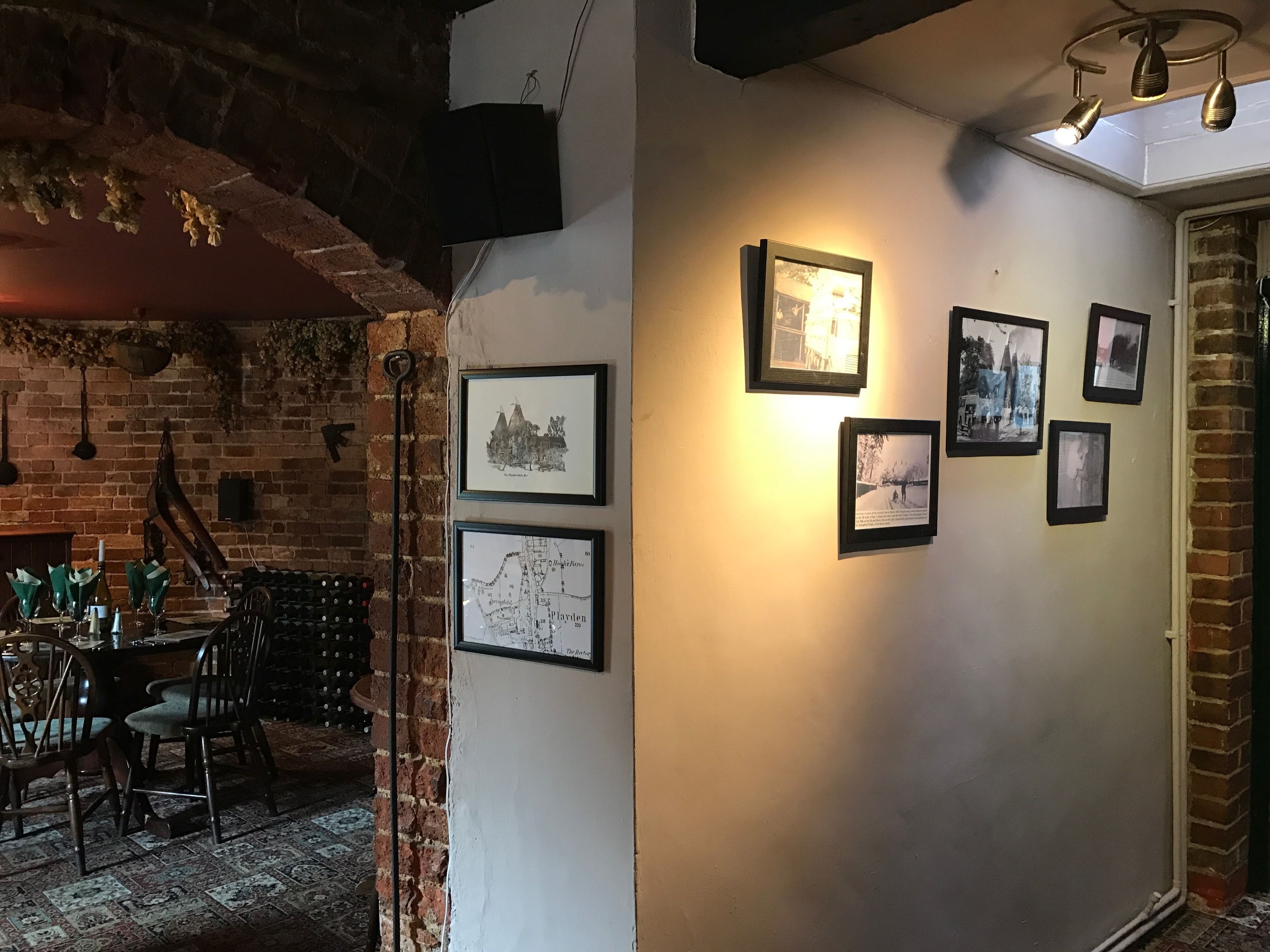 A room with a brick wall, a table with chairs, and framed pictures on the wall.
