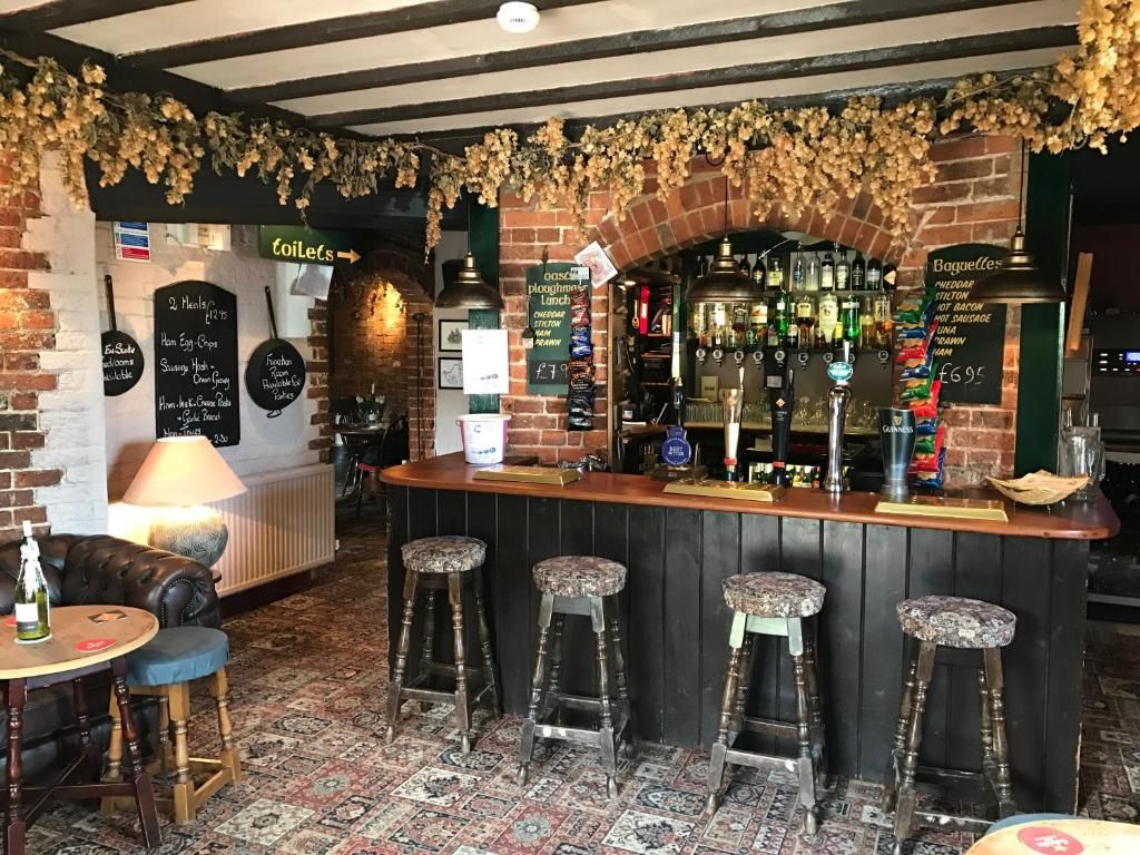 Eine Bar mit Backsteinwand, Barhocker, einer Theke mit Flaschen und einer Speisekarte.