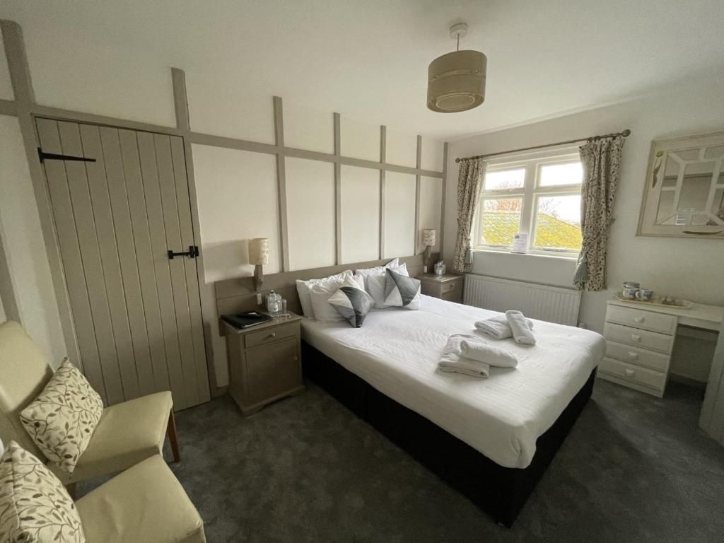 Une chambre à coucher avec un lit, des tables de chevet, une chaise, une fenêtre et un radiateur.