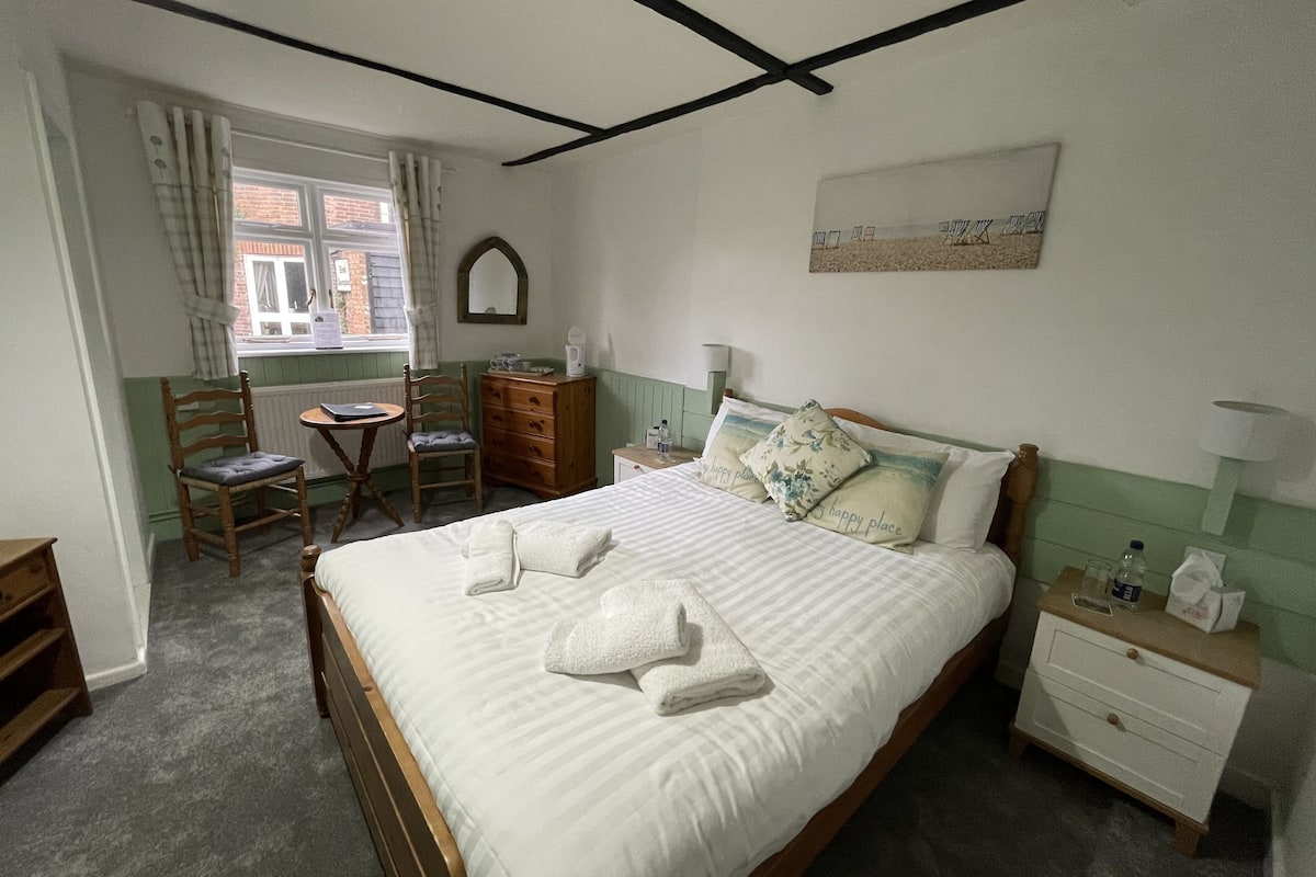 Une chambre bien rangée, avec un lit, un bureau, une chaise et une commode.