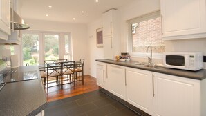Una cocina moderna con armarios blancos, encimera de granito y microondas integrado.