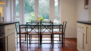 Comedor con mesa y sillas, ventanas amplias y vista a zonas verdes.