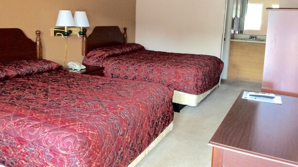 A hotel room with two beds, a desk, a mirror, and a nightstand with lamps. - Budget Inn (Calhoun)