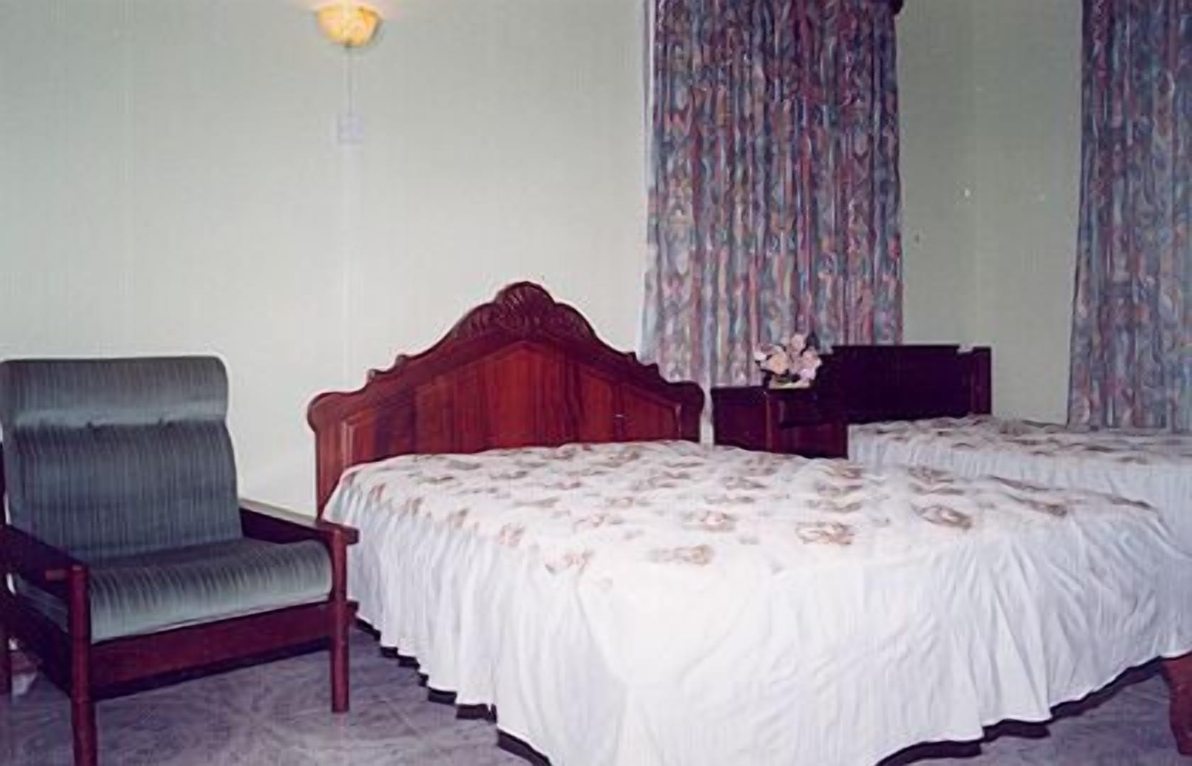 A bedroom with a single bed, a chair, and a nightstand.