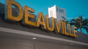 Ein Hotel-Schild mit dem Namen 'DEAUVILLE' in großen, goldenen Lettern.