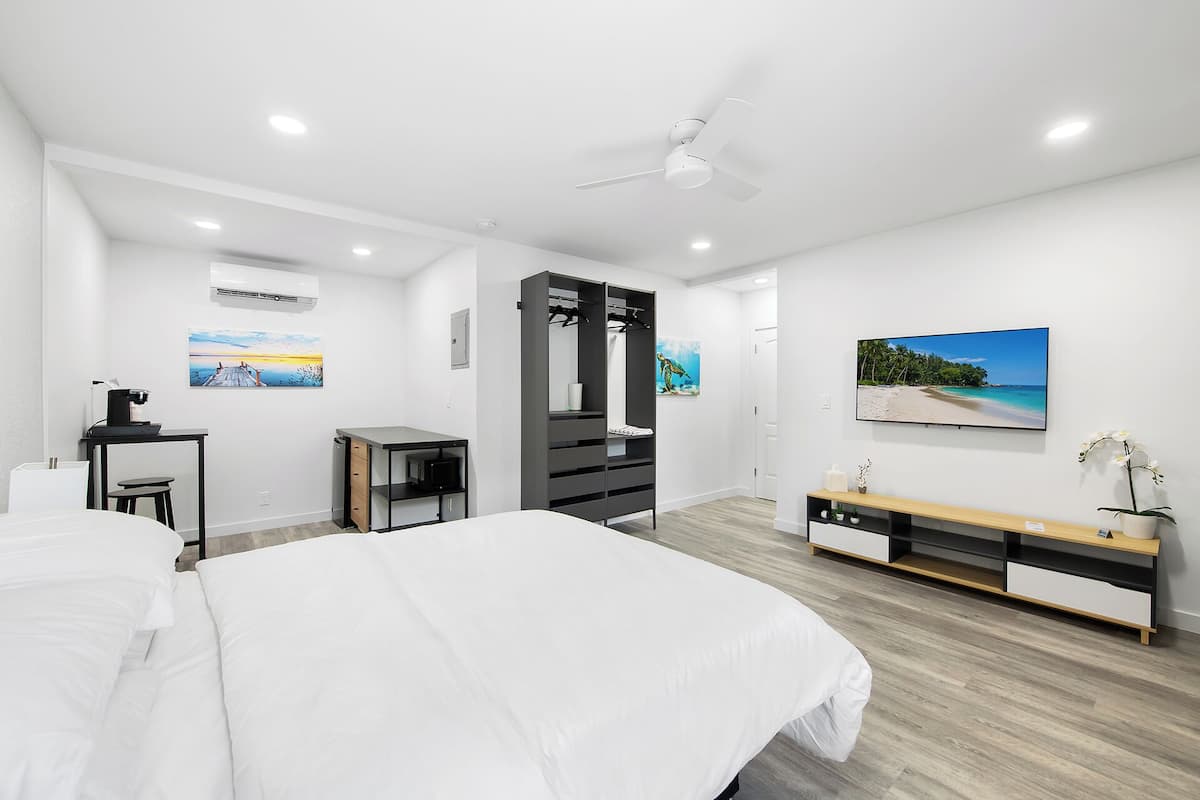 Un dormitorio moderno con una cama grande, un escritorio, un armario y un televisor.