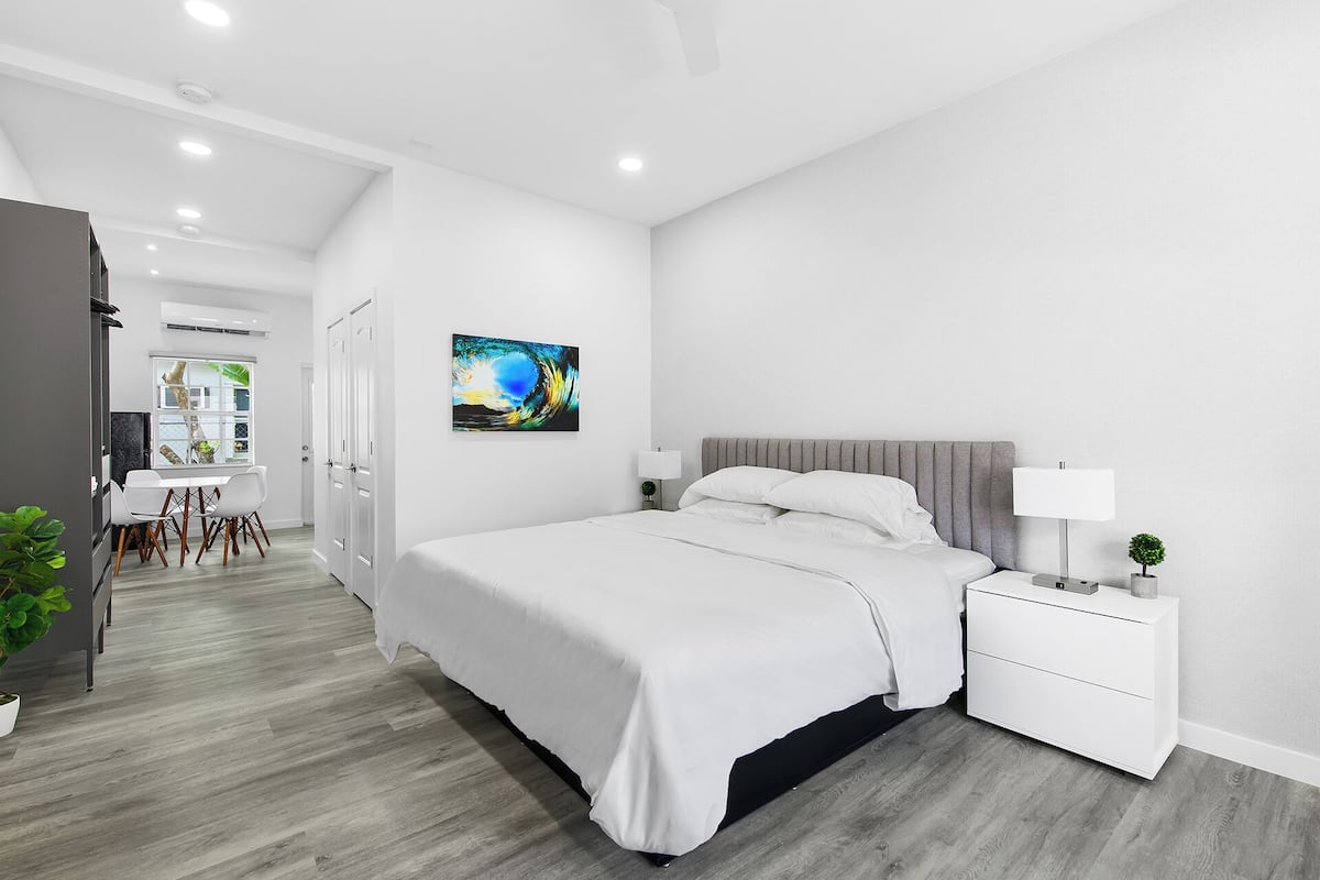 Un dormitorio moderno con una cama grande, mesitas de noche y un cuadro en la pared.