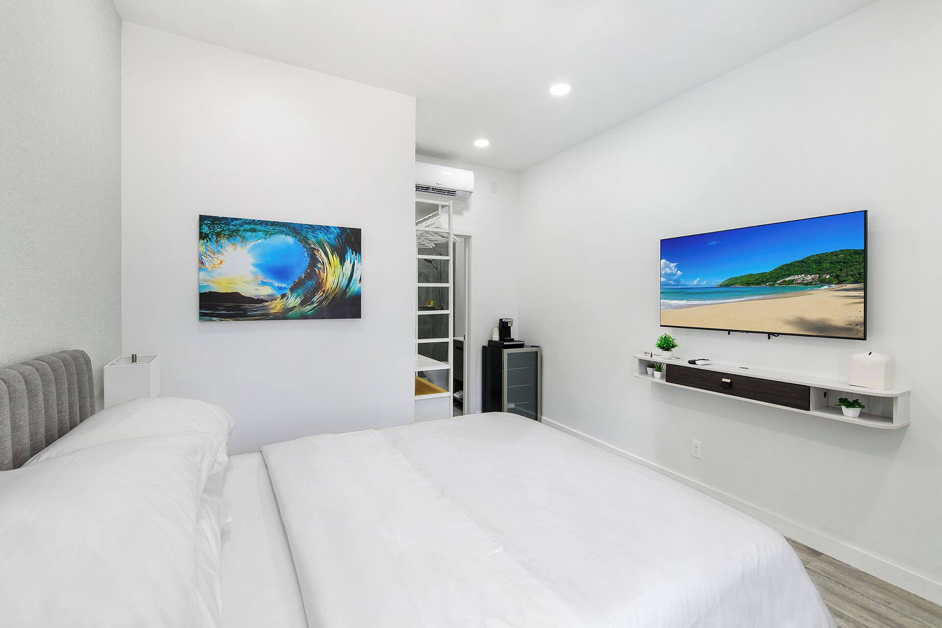 A modern hotel room with a large bed, a flat-screen TV, and two wall-mounted paintings.